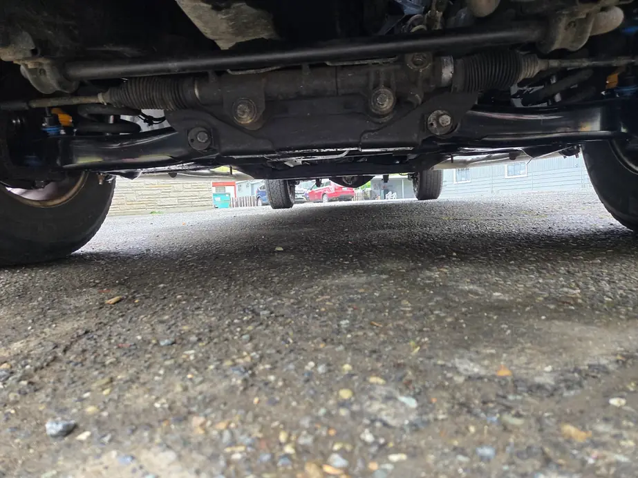 Looking along the underside of a vehicle at the steering rack and front subframe